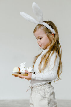 Blonde cheerful kid with Easter eggs and in bunny ears