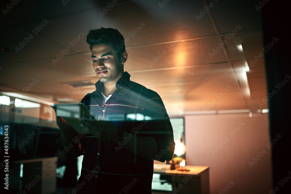 Poster all nighters are nothing for a get it done guy. shot of a young businessman using a digital tablet d