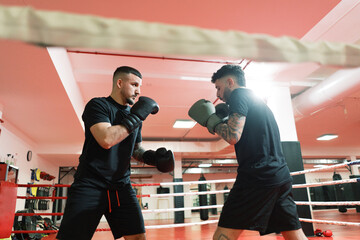 Sportsmen boxing on ring in gym