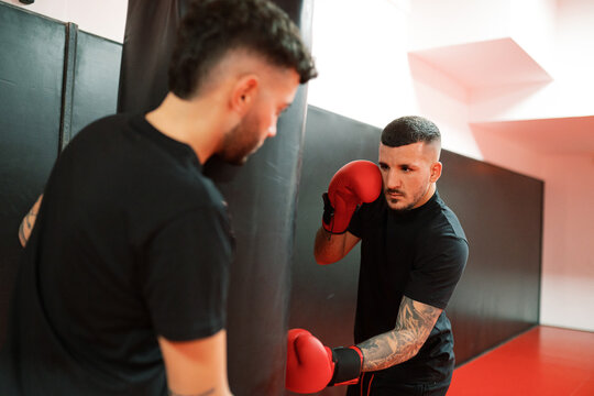 Male boxer exercising with friend in gym