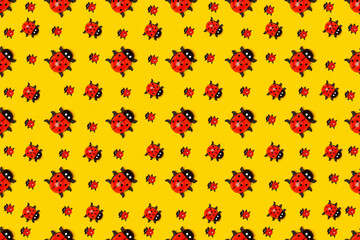 Pattern made with ladybugs on yellow background, as backdrop or texture. Bright summer wallpaper. Top view Flat lay