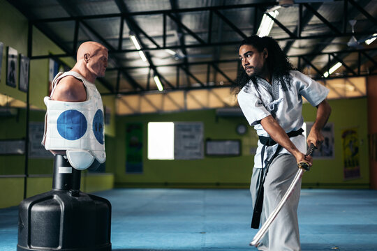 Man training martial arts with katana with a dummy