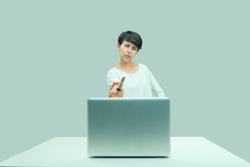 Angry ordinary young woman middlefingers toward her laptop