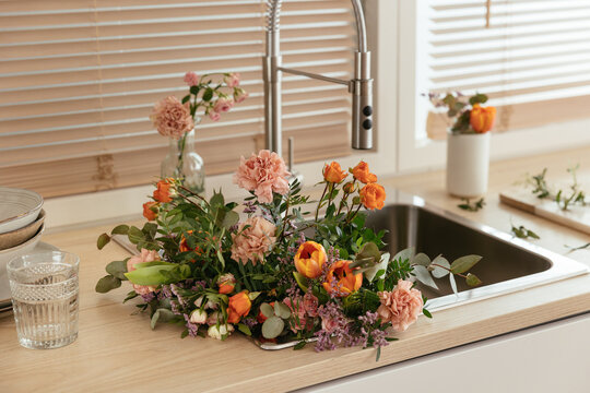 Bunch of assorted flowers in sink in kitchen