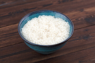 Obraz na płótnie Canvas A bowl of raw white rice on a wooden table