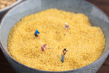 Miniature creative workers in a bowl of millet