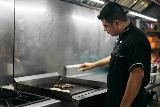 Mexican chef cooking tacos in professional kitchen