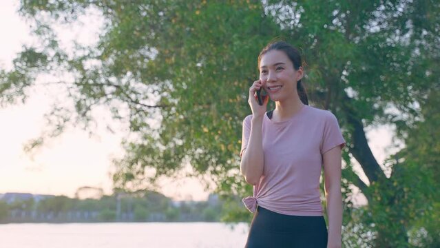 Asian young woman stand outdoor use mobile phone call talk with friend