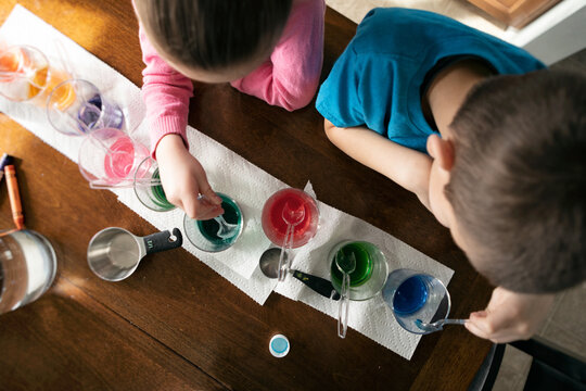 Children Stirring Easter Egg Dye In Glasses