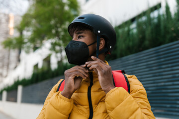 Young male courier preparing for ride