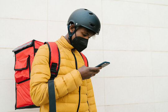 Delivery man in mask checking address on cellphone