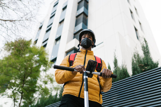 Delivery man with kick scooter on street