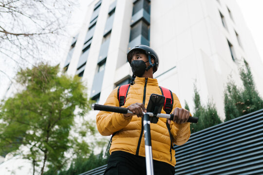 Male courier with kick scooter in city