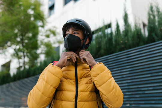 Delivery man fastening helmet on street