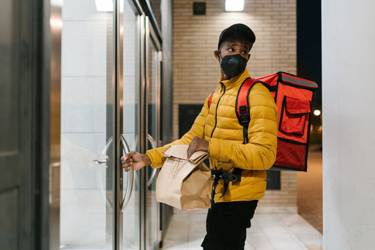 Delivery man with order standing near entrance