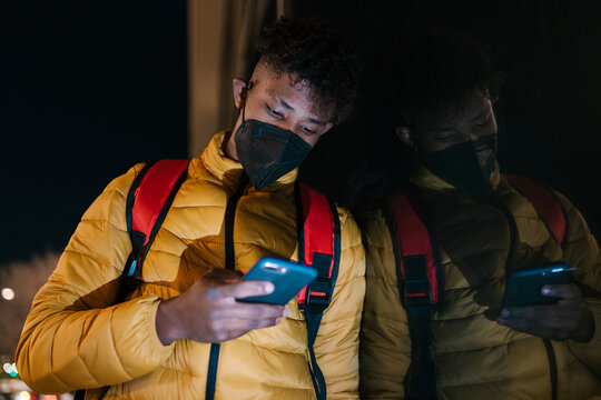 Male courier browsing app on smartphone on street