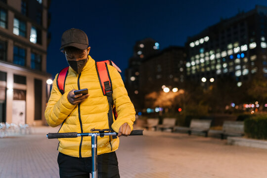 Black courier checking route on smartphone at night