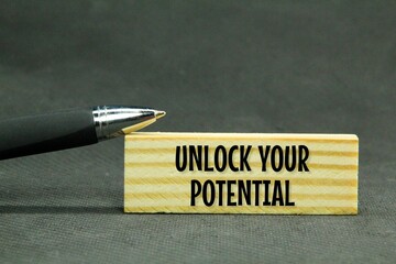 pen and wooden board with the words unlock your potential