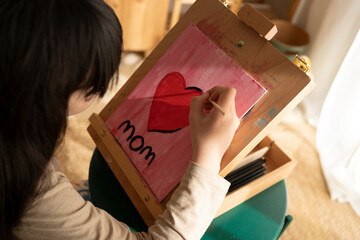 Girl painting a heart on tabletop easel