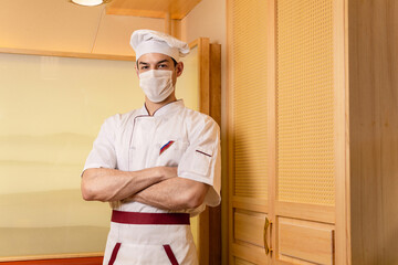 Male chef cook wearing face protective medical mask for protection from virus disease at restaurant kitchen. Health, safety and pandemic concept