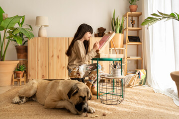Girl drawing with big dog at home 