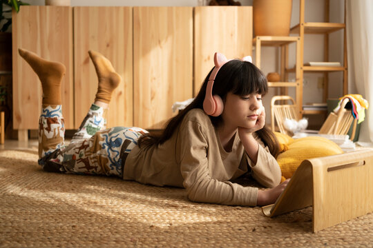 Girl watching tablet on support at living room floor