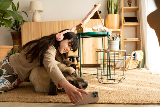Girl taking selfie with her dog at living room floor