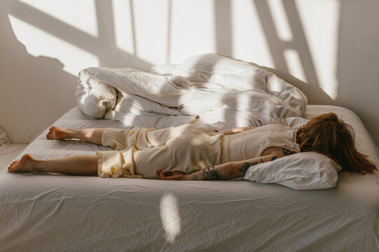Depressed woman lying face down on bed