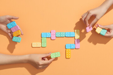 Two women playing domino on beige background