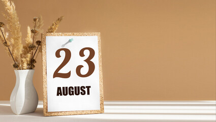 august 23. 23th day of month, calendar date.White vase with dead wood next to cork board with numbers. White-beige background with striped shadow. Concept of day of year, time planner, summer month