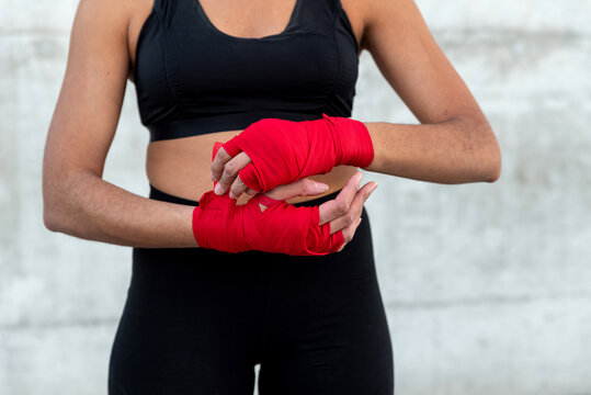 Crop sportswoman in red fighting bandages in city