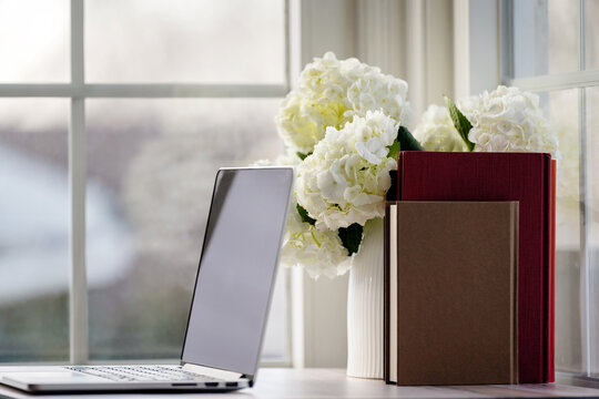 Laptop and fresh flowers by the window