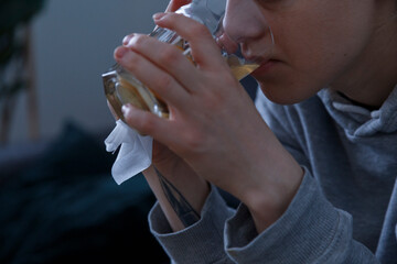Crop ill woman drinking hot beverage from glass