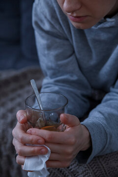 Crop ill woman with glass of warm tea
