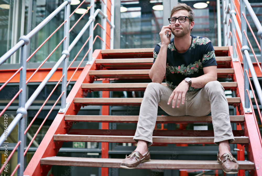 Poster staying in touch with his clients. shot of a handsome young man using his mobile phone while sitting