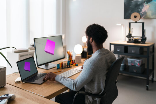 Bearded man creating draft of 3D figure on devices
