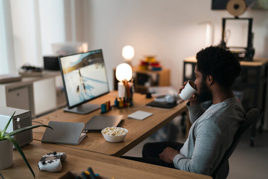 Calm guy drinking coffee while watching movie on PC