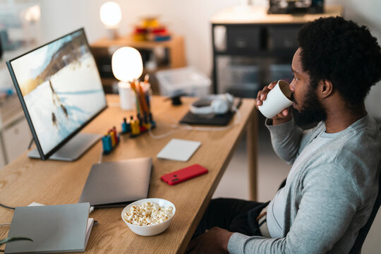 Calm guy drinking coffee while watching movie on PC