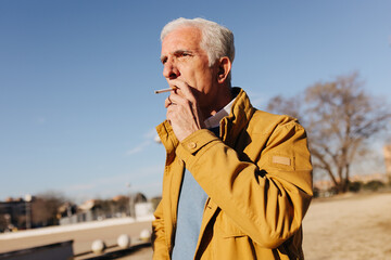 Senior man smoking a cigarette in the street