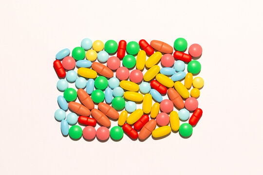 Scattered colorful pills/drugs against white background