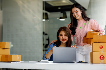 Portrait of Starting small businesses SME owners, two Asian woman check online orders Selling products working with boxs freelance work at home office, sme business online small medium enterprise