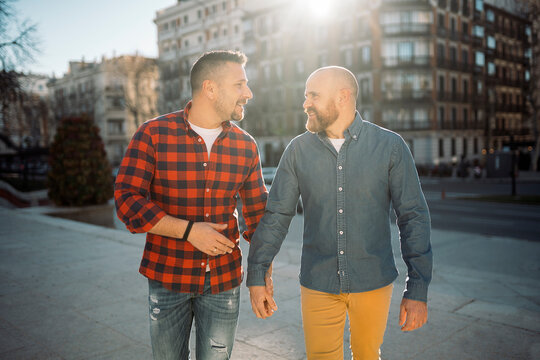 Positive Gay Couple Holding Hands During Stroll In City