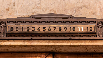 An Art Deco styled elevator floor indication made from brass set into a marble wall with the 11th floor Illuminated