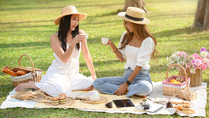 Two beautiful young women enjoying an afternoon tea picnic in the garden