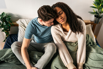 Interracial couple in bed at home during day off