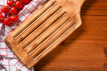 Vintage dining table setting with empty wooden board, fresh tomatoes, red and white tablecloth