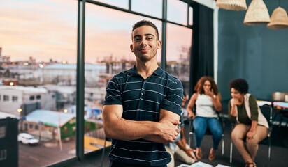 He has big dreams for their small business. Portrait of a cheerful young man standing with his arms...