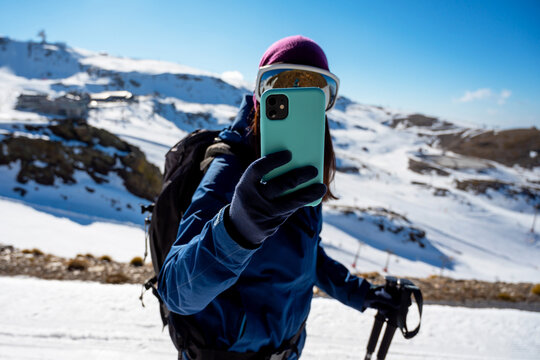 Climber taking picture on smartphone in snowy highlands