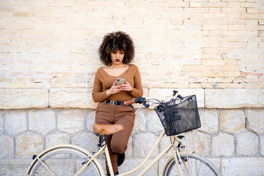 Serious woman texting message on smartphone near bike
