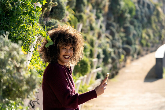 Happy curly haired woman browsing smartphone